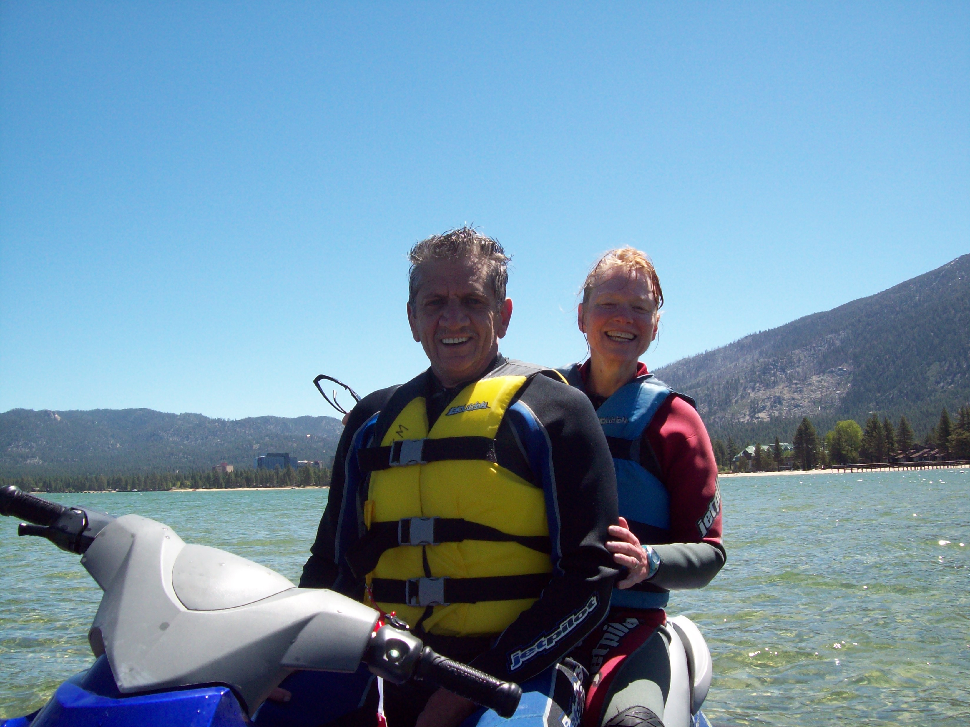 A couple enjoying a thrilling ride on a jet ski together, surrounded by sparkling blue water under a clear sky.
